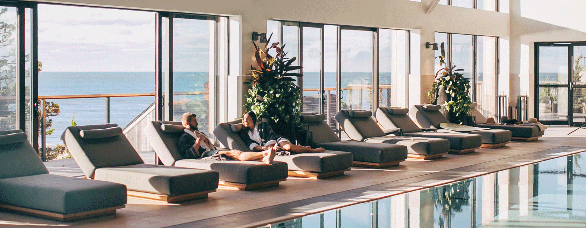 GIF showing couple lounging by indoor pool, waves crashing in front of pink skyline, shoreline view of 168极速赛车官方开奖结果记录体彩 Resort & 极速赛车168一分钟开奖记录体彩-开奖结果预测官网直播 seawater spa.