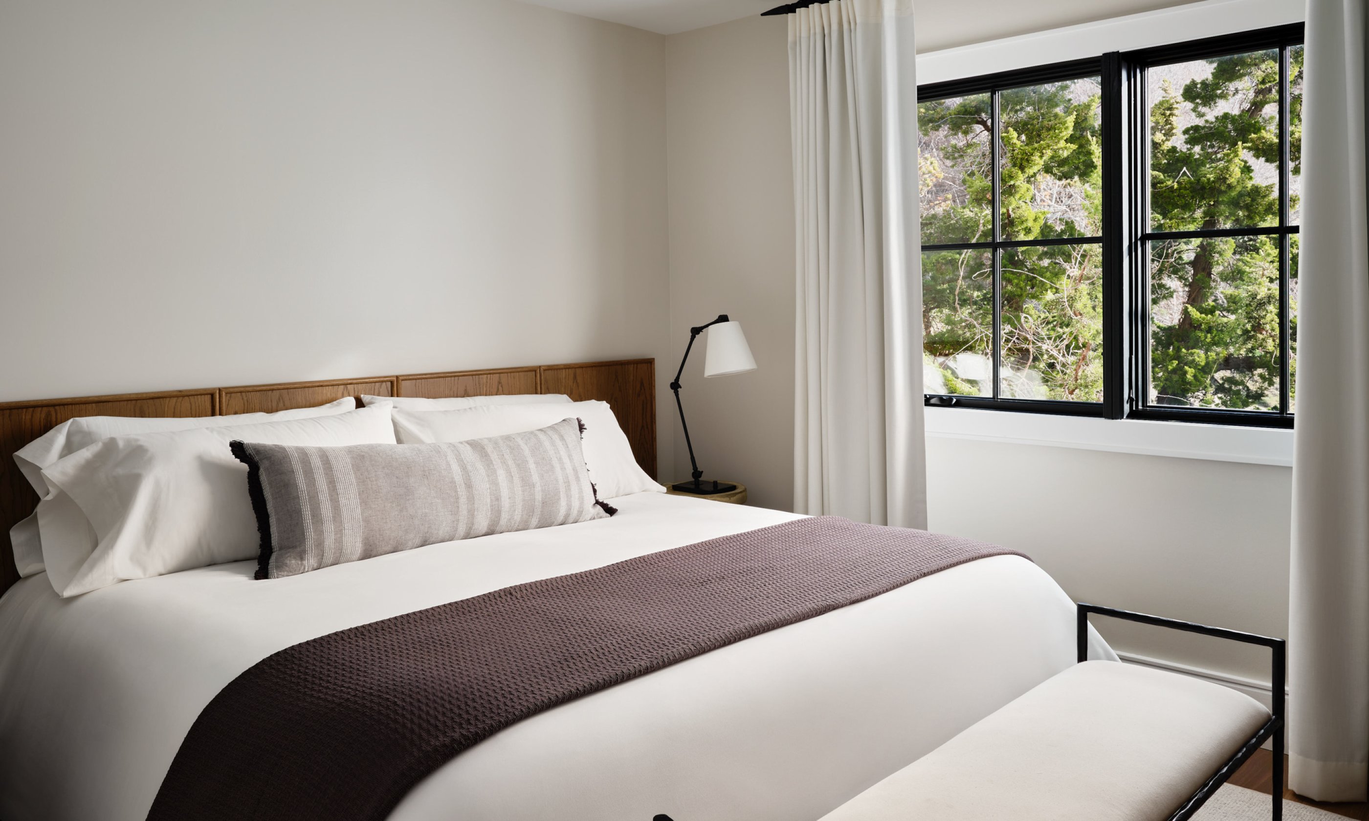 Bedroom with king bed, throw blanket, nightstand and window.