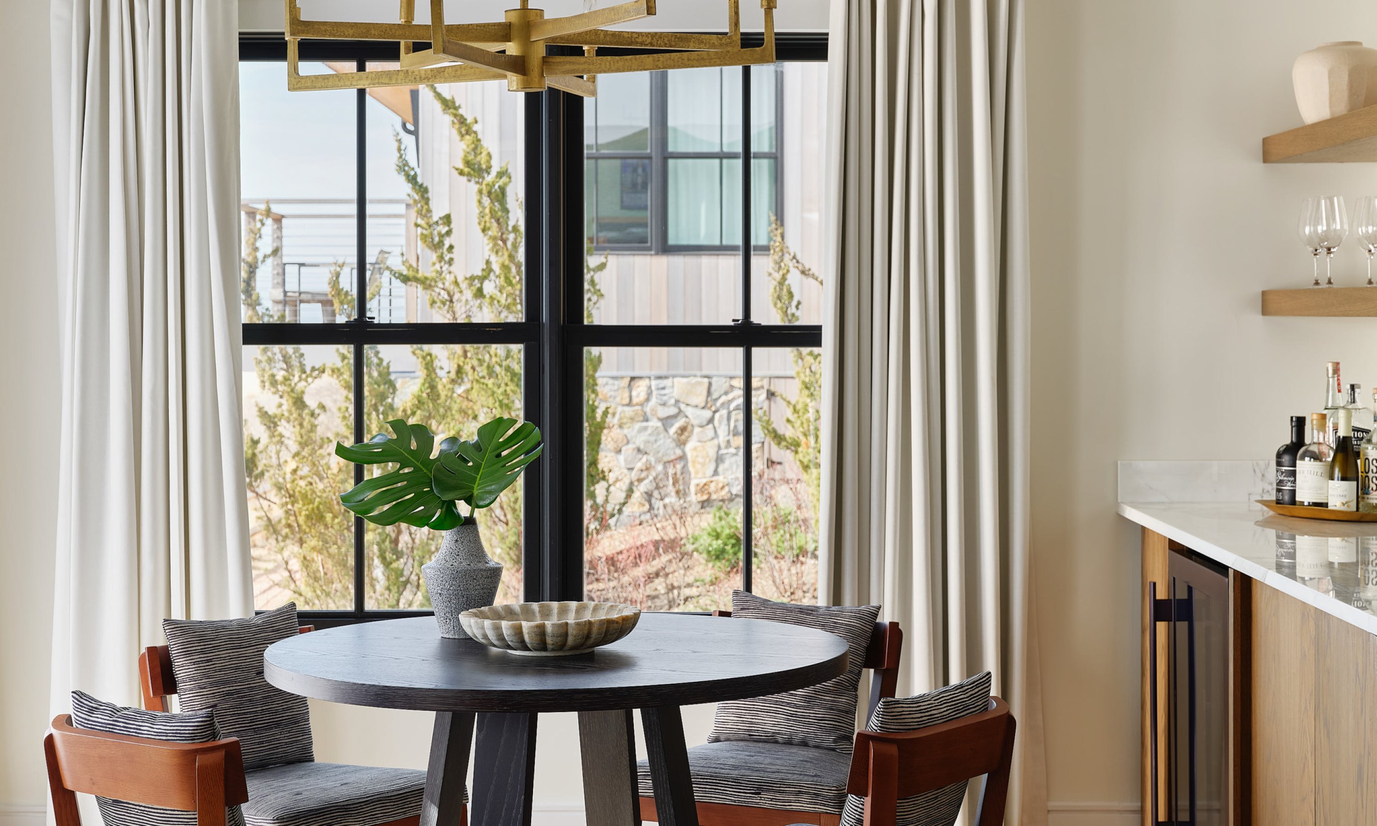 Dining table with chandelier and nearby wet bar.