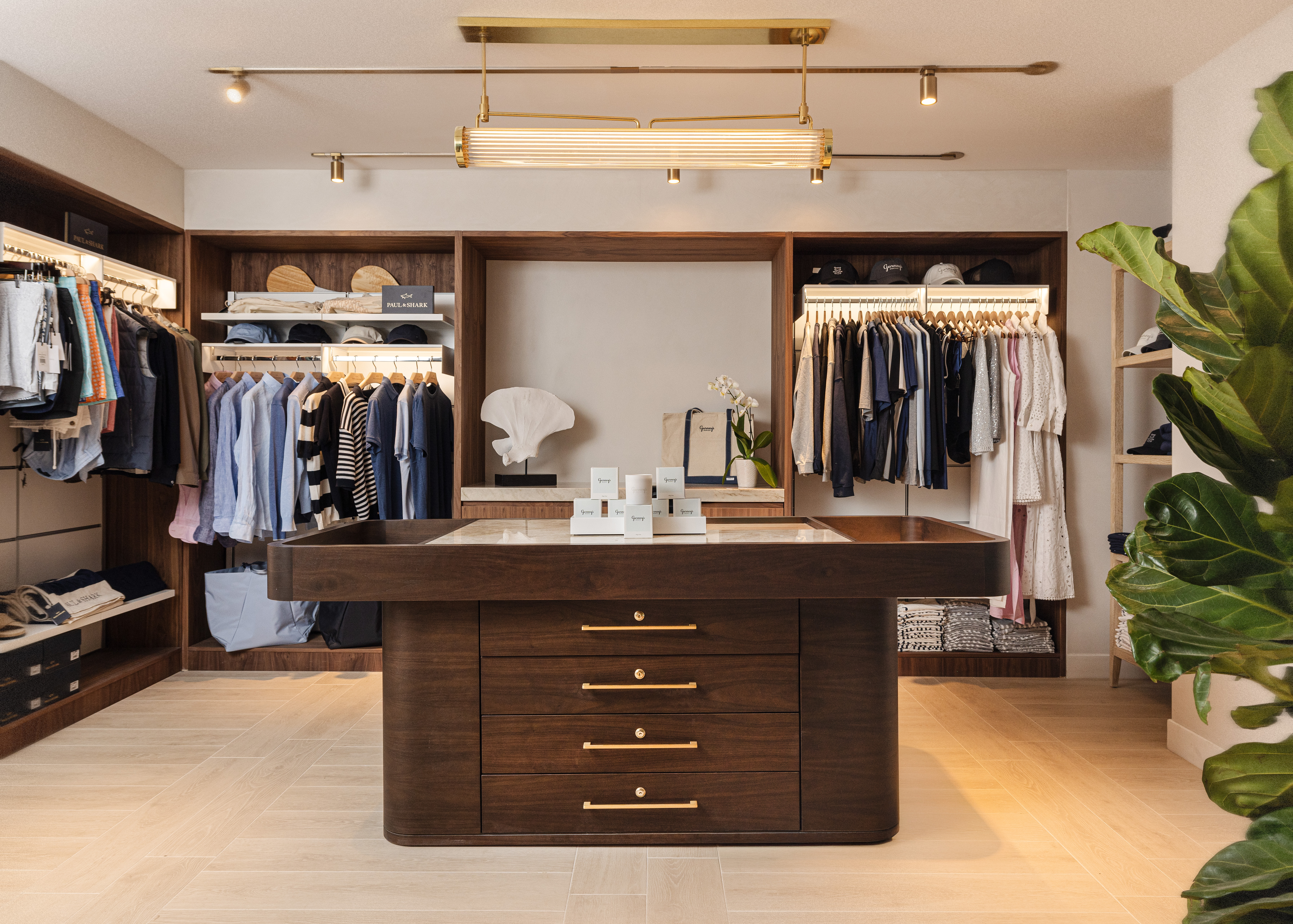 Retail shop with clothing on racks and a brown wood table centered
