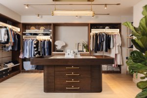 Retail shop with clothing on racks and a brown wood table centered