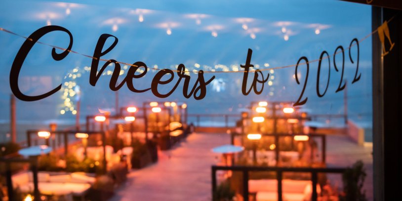 Festive outdoor seating with string lights and "Cheers to 2022" written in the foreground.