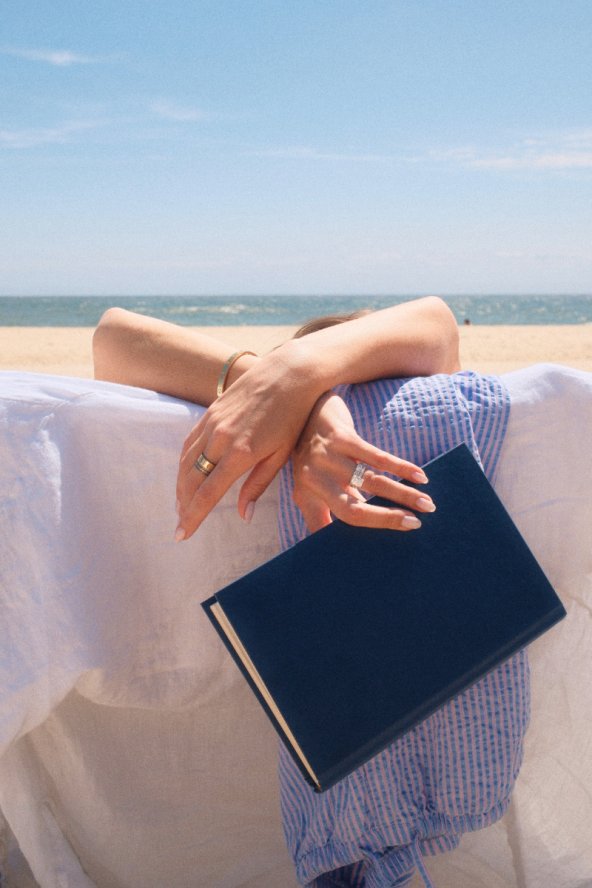 Girl holding book in her beach chair