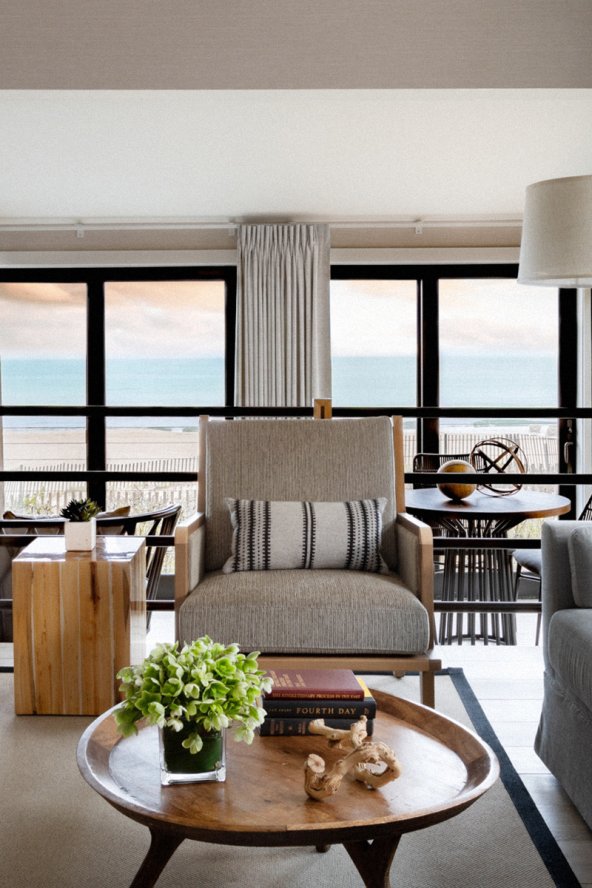 Sitting area with sofa, armchairs, and coffee table, with a view out onto the beach