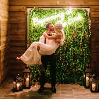 groom holding bride in front of step and repeat