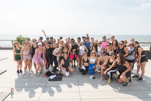 Mixed group in fitness attire huddled up for a photo on Gurney's outdoor fitness deck.