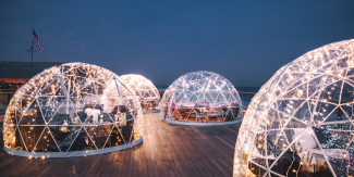 Warmly lit clear igloos against a dark blue evening sky at Gurney's Montauk Resort